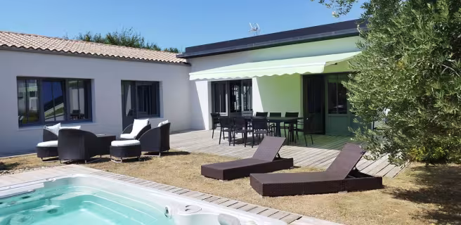 La piscine extérieure découverte, entourée par la maison, des salons de jardins et transats.